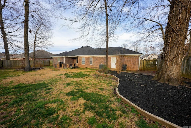 rear view of property with brick siding, central AC unit, a lawn, and a fenced backyard