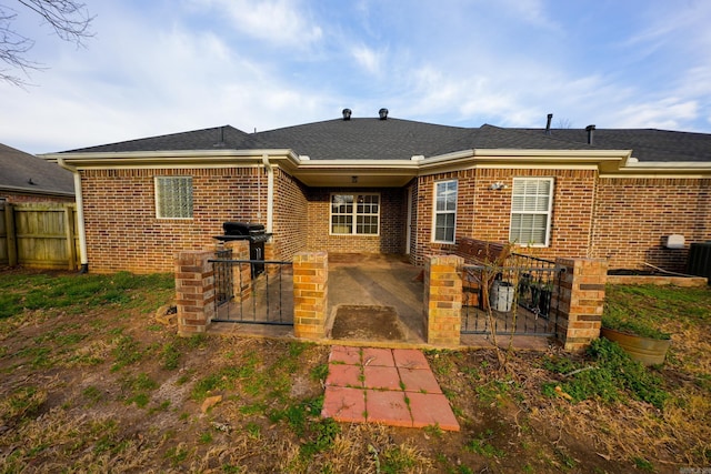 rear view of property featuring a patio, brick siding, and fence