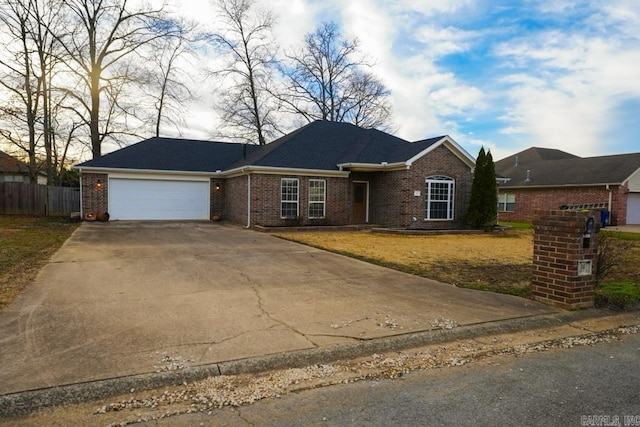 single story home with driveway, brick siding, fence, a garage, and a front yard