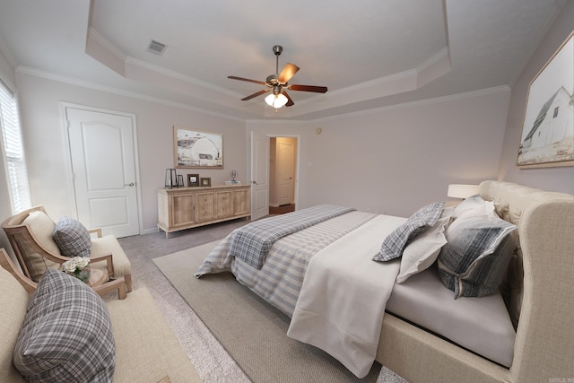 bedroom with carpet, a tray ceiling, visible vents, ceiling fan, and ornamental molding