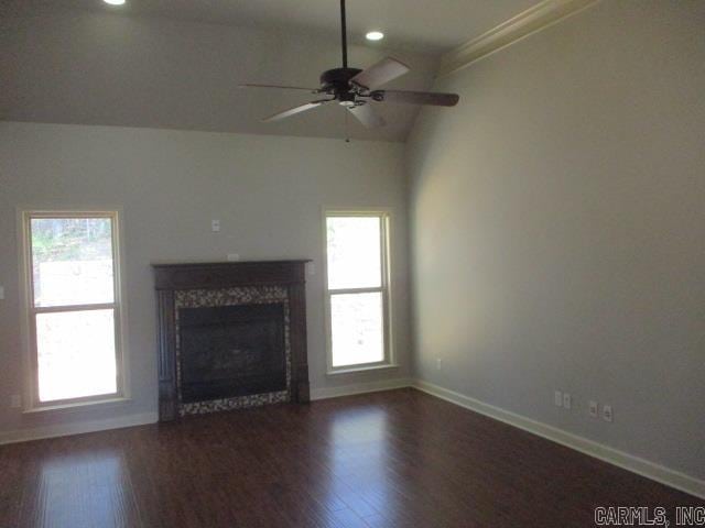 unfurnished living room featuring ceiling fan, a wealth of natural light, baseboards, and wood finished floors