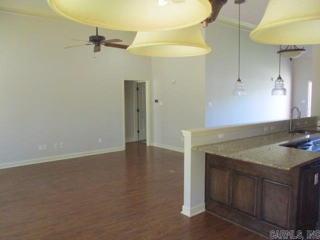 kitchen featuring a sink, dark wood-style flooring, a ceiling fan, light stone countertops, and baseboards