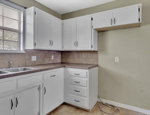 kitchen with white cabinetry, decorative backsplash, light tile patterned floors, and a healthy amount of sunlight