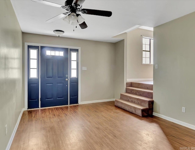 foyer with ceiling fan, baseboards, a healthy amount of sunlight, and wood finished floors