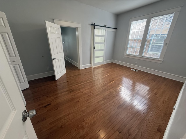 315 W 22nd St, Little Rock, AR 72206 - unfurnished bedroom featuring dark wood-style floors, a barn door, and baseboards