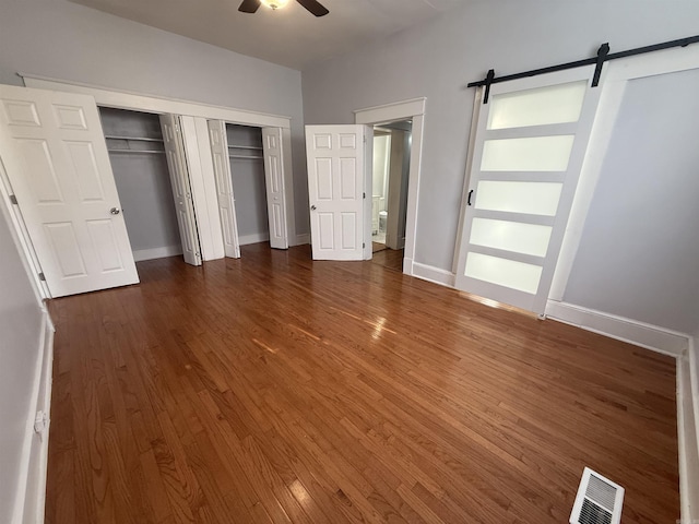 315 W 22nd St, Little Rock, AR 72206 - unfurnished bedroom with a barn door, wood finished floors, baseboards, and ceiling fan