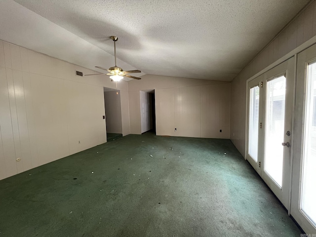 empty room featuring a ceiling fan, light carpet, a textured ceiling, visible vents, and vaulted ceiling