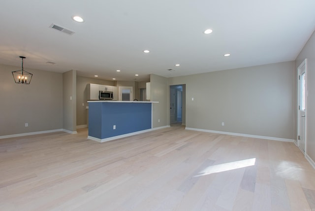 unfurnished living room with a chandelier, light wood-type flooring, visible vents, and recessed lighting