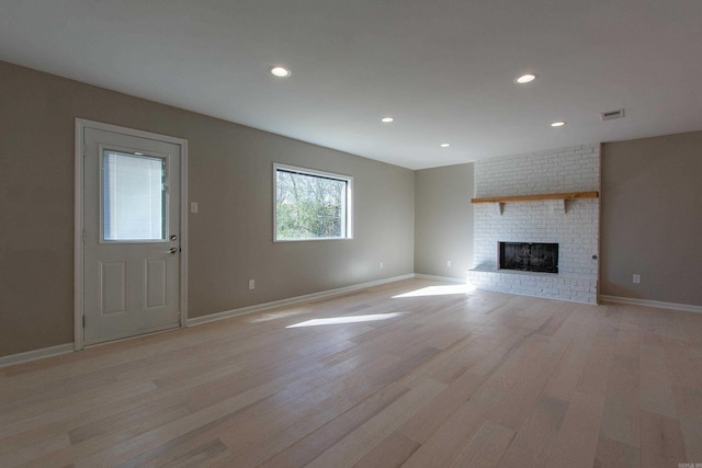 unfurnished living room featuring visible vents, light wood-style flooring, a brick fireplace, and recessed lighting