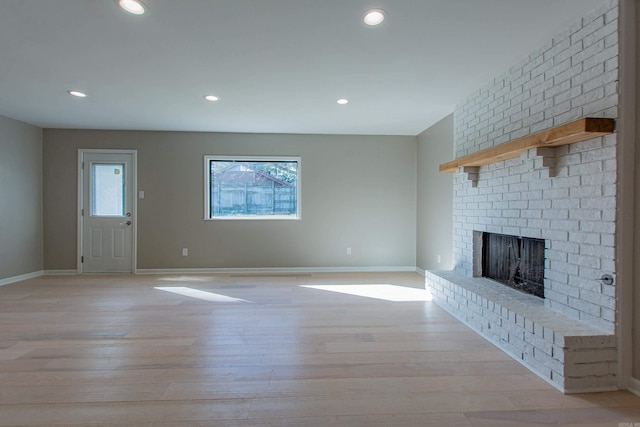 unfurnished living room featuring baseboards, a fireplace, recessed lighting, and light wood-style flooring