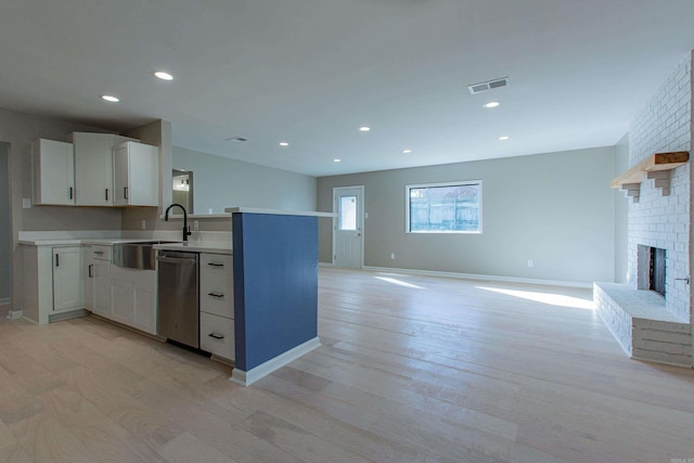 kitchen featuring light countertops, light wood-type flooring, a sink, and dishwasher