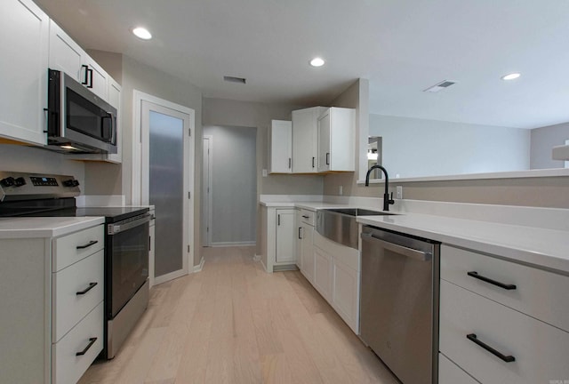 kitchen with stainless steel appliances, light wood finished floors, visible vents, a sink, and light countertops
