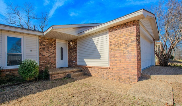 doorway to property with a garage and brick siding