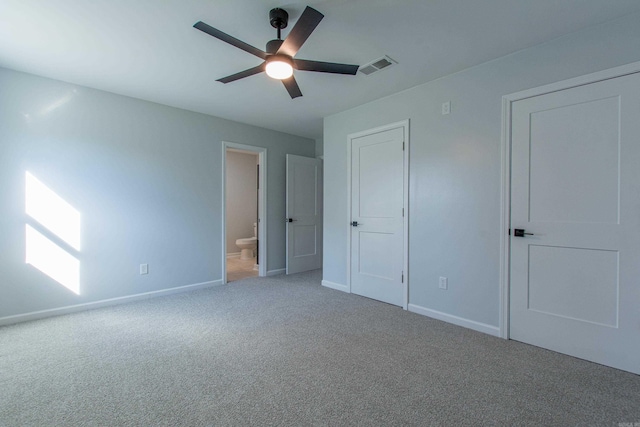 unfurnished bedroom with a ceiling fan, carpet floors, ensuite bathroom, visible vents, and baseboards