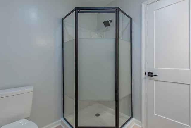 full bathroom featuring toilet, baseboards, and a shower stall