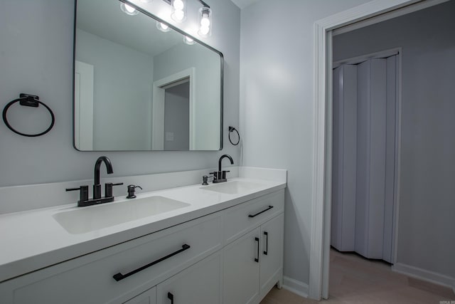 full bathroom with a sink, double vanity, and baseboards