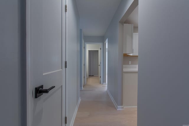 hall featuring light wood-style flooring and baseboards