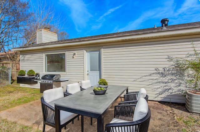 view of patio featuring central AC, fence, outdoor dining space, and grilling area