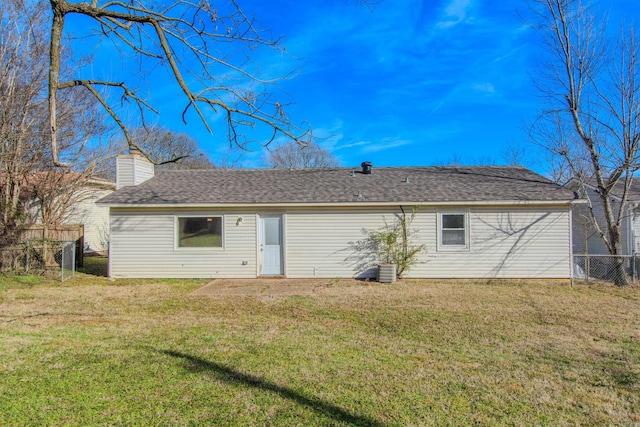 back of house with a yard, roof with shingles, fence, and a chimney
