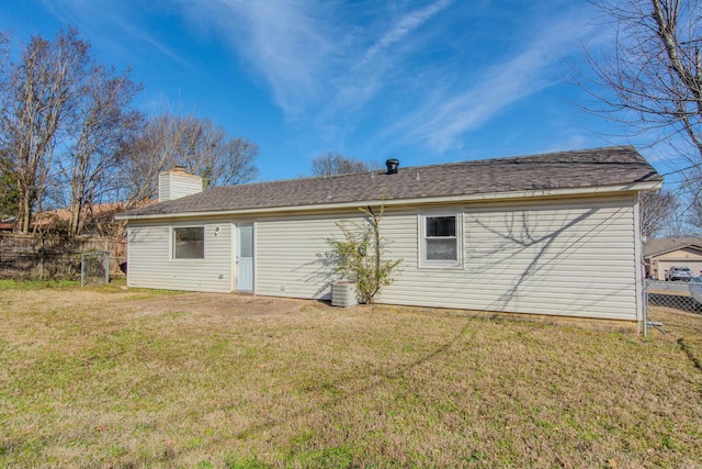 back of house with a yard, central air condition unit, a chimney, and fence