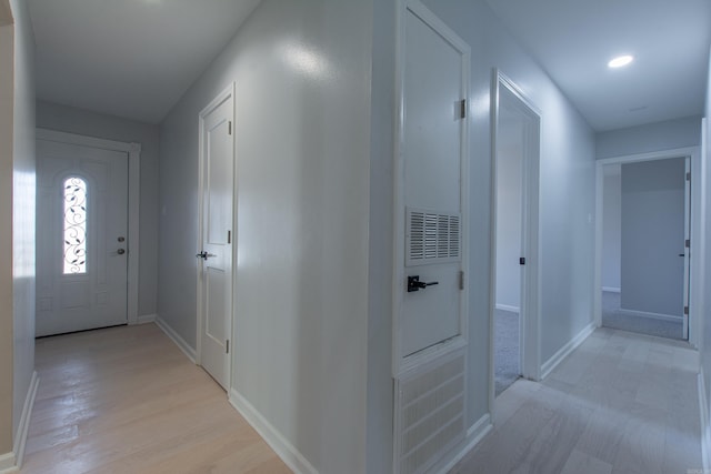 hallway with baseboards, light wood-type flooring, and recessed lighting