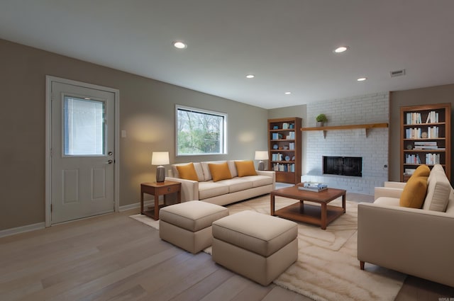 living room featuring recessed lighting, light wood finished floors, a fireplace, and visible vents