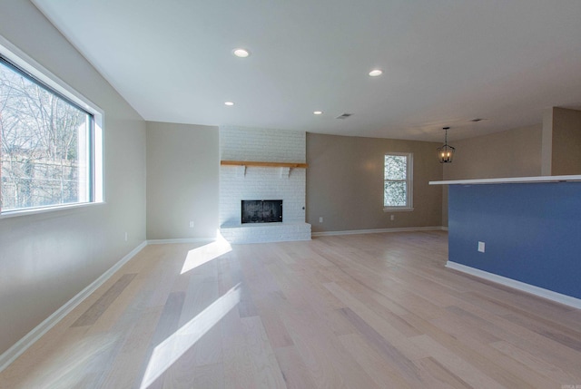 unfurnished living room featuring a fireplace, light wood-type flooring, and a chandelier