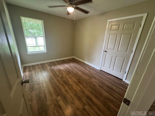 unfurnished bedroom with baseboards, dark wood-style flooring, and ceiling fan