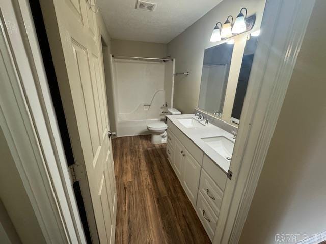 full bath featuring toilet, visible vents, wood finished floors, and a sink