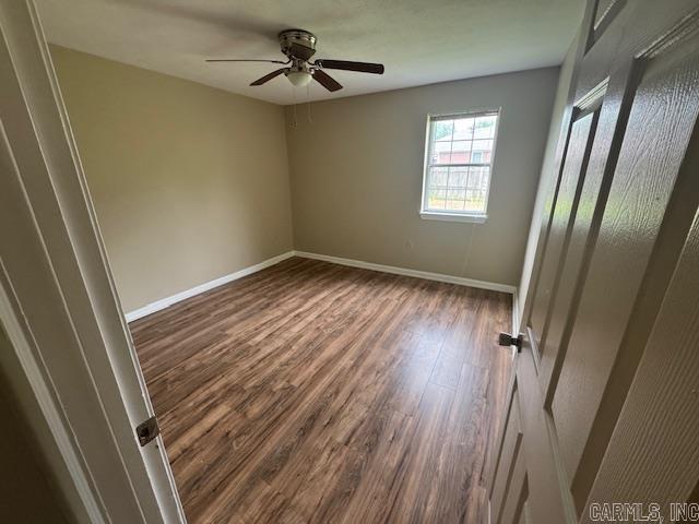 unfurnished bedroom with a ceiling fan, dark wood-style flooring, and baseboards