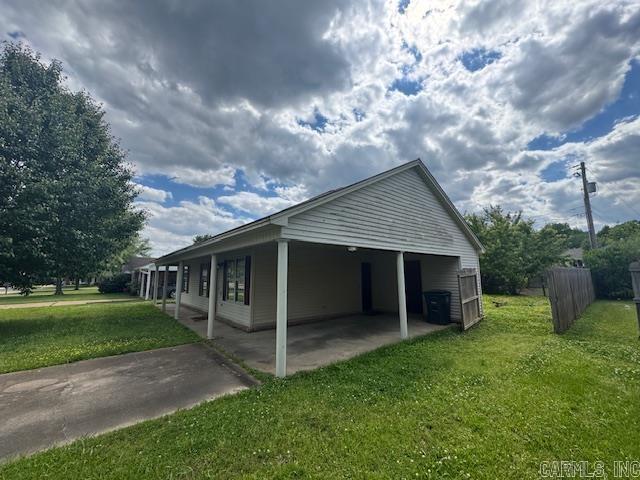 view of side of property with a patio, fence, a lawn, and a carport