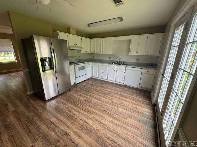 kitchen featuring a sink, dark wood finished floors, visible vents, white appliances, and under cabinet range hood