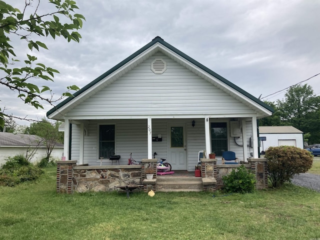 back of property with covered porch and a yard