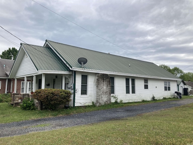 view of front of house with metal roof, a porch, and a front lawn