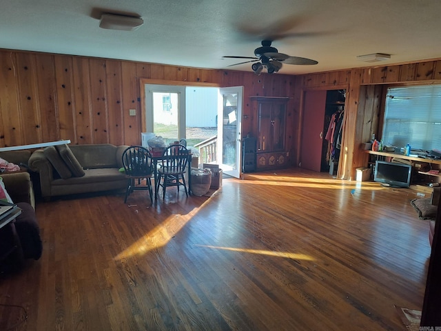 207 11th St, Mena, AR 71953 - living area with wood walls, a ceiling fan, and wood finished floors