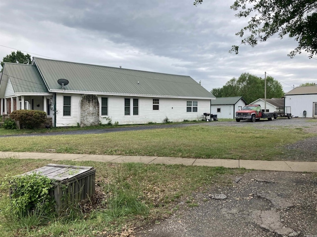 view of front of home featuring metal roof and a front lawn