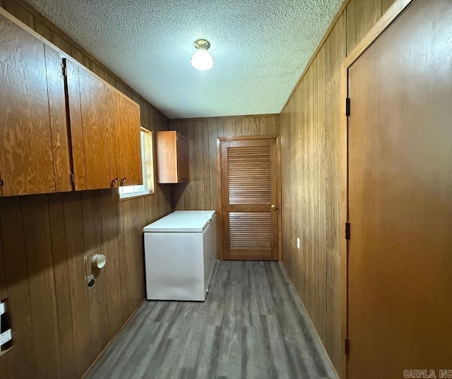 1300 Overdene St, Corning, AR 72422 - clothes washing area with cabinet space, a textured ceiling, wood walls, and light wood-style flooring
