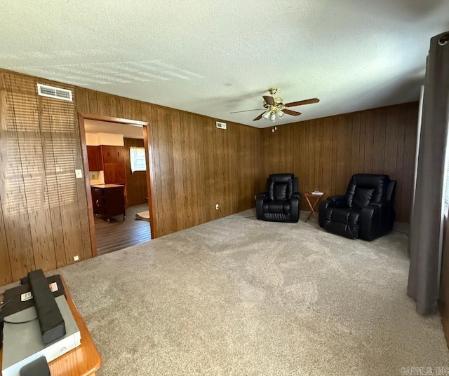 1300 Overdene St, Corning, AR 72422 - living area featuring a ceiling fan, carpet floors, a textured ceiling, visible vents, and wooden walls