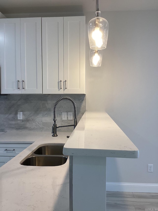 312 Frank T Bunton St, Lonoke, AR 72086 - kitchen featuring a sink, a peninsula, tasteful backsplash, white cabinetry, and baseboards