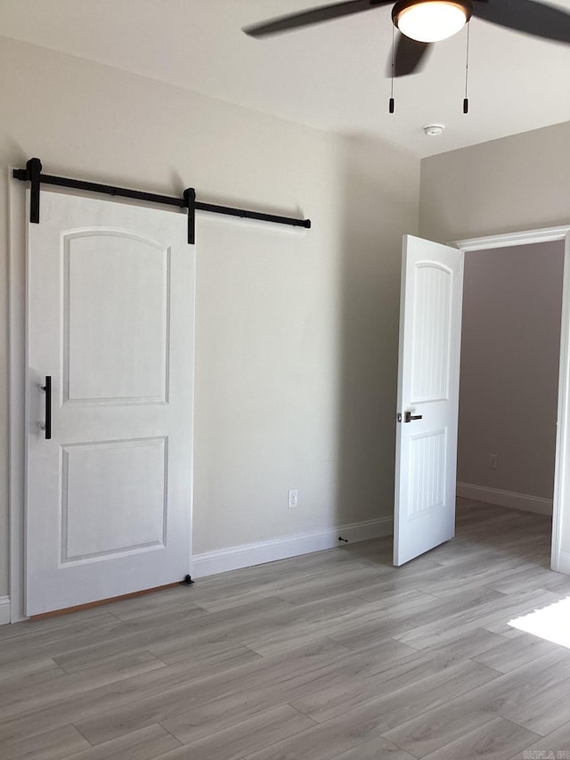 312 Frank T Bunton St, Lonoke, AR 72086 - unfurnished bedroom with a barn door, light wood-type flooring, and baseboards