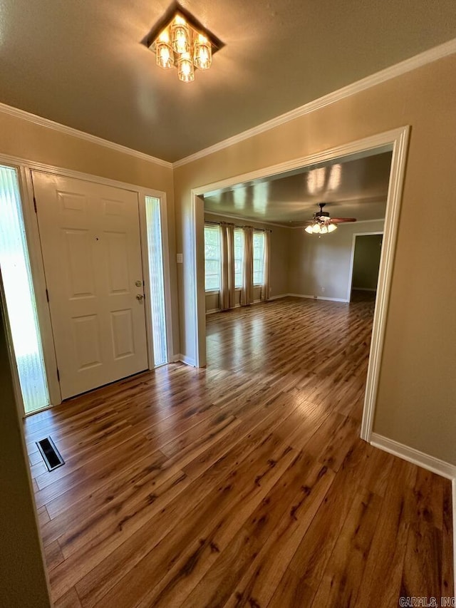 foyer featuring ornamental molding, ceiling fan with notable chandelier, baseboards, and wood finished floors