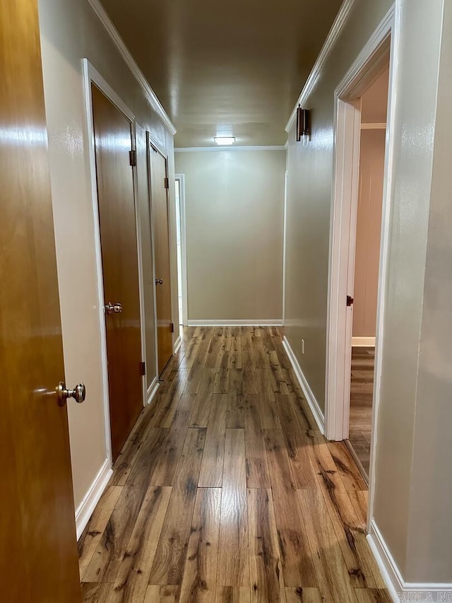 corridor featuring baseboards, ornamental molding, and hardwood / wood-style flooring