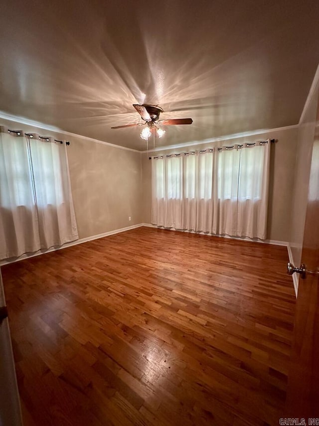 empty room with baseboards, ornamental molding, ceiling fan, and wood finished floors