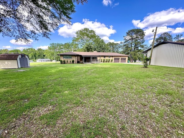 back of house with an attached garage, a yard, an outbuilding, and a storage unit