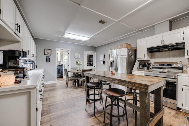 kitchen featuring light wood-style flooring, stainless steel appliances, visible vents, under cabinet range hood, and light countertops