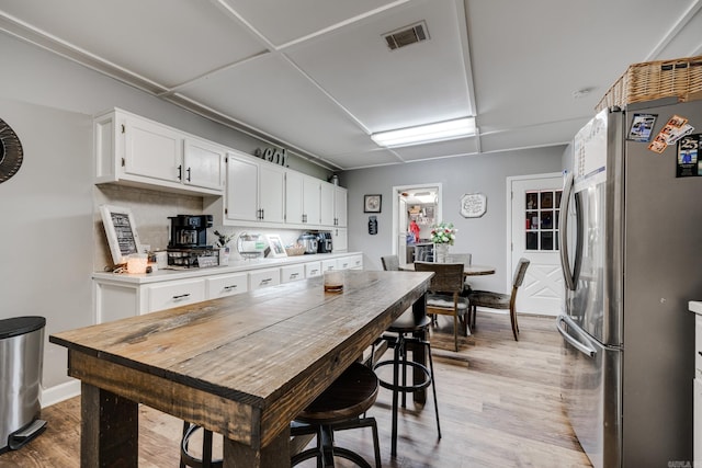 kitchen with freestanding refrigerator, baseboards, light wood finished floors, white cabinetry, and light countertops