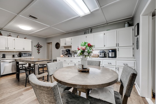 dining area featuring light wood finished floors, visible vents, and a toaster