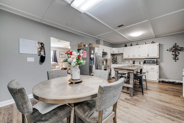 dining area featuring light wood-style floors, visible vents, and baseboards