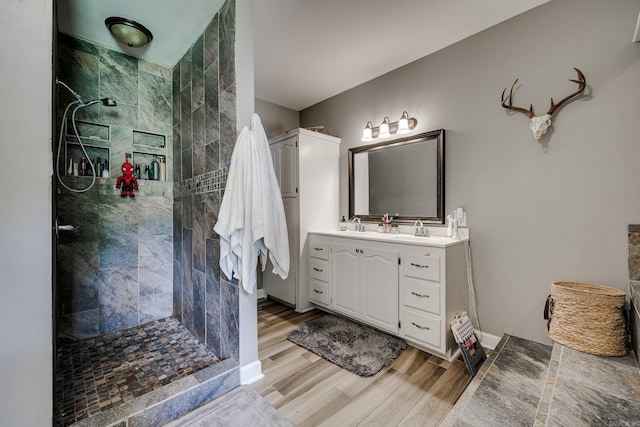 bathroom featuring a walk in shower, vanity, and wood finished floors