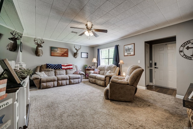 living room with carpet flooring, ornamental molding, visible vents, and ceiling fan
